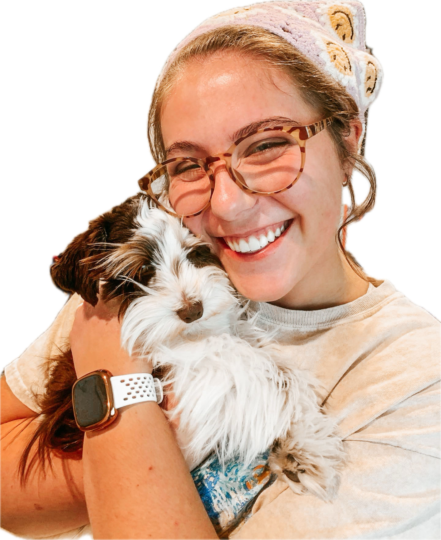 Sophia Wall, The artist of wallie art studio, wearing glasses and a headband, and smiling while holding a brown and white spotted toy schnauzer named Hazel